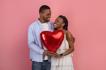 Fototapeta na wymiar Young Romantic Black Couple Hugging And Holding Heart Shaped Balloon