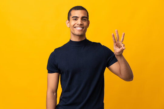 African American man counting numbres over isolated yellow background