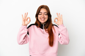 Young redhead woman isolated on white background in zen pose