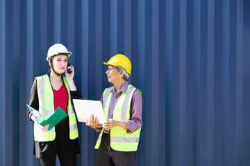 Manager controller woman and logistics man worker wear safety helmets and protect suite checking containers box and loading products from Cargo freight ship at Cargo container.