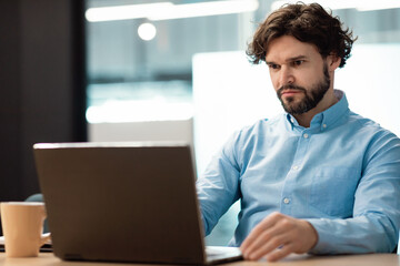 Business man using laptop sitting at desk in office