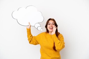 Young redhead woman isolated on white background holding a thinking speech bubble and shouting