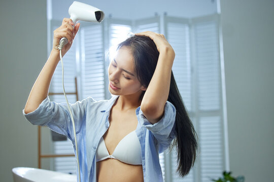 A beautiful young woman use hair dryer