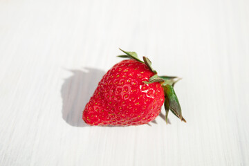 strawberries close-up on white wooden background in sunlight