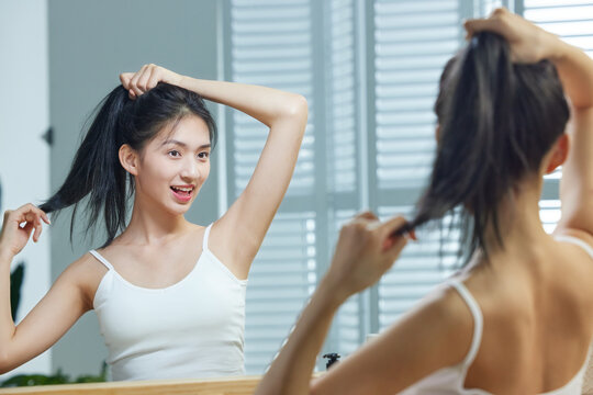 A beautiful young woman look into a mirror whilst combing your hair