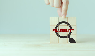 Feasibility study, business investment concept. Assessing the practicality of a proposed plan or project for launching a new business or adopting a new product line.  Magnifier and feasibility text.