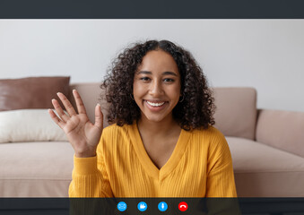 Head shot of happy young black woman waving at webcam, greeting friend or teacher during remote...