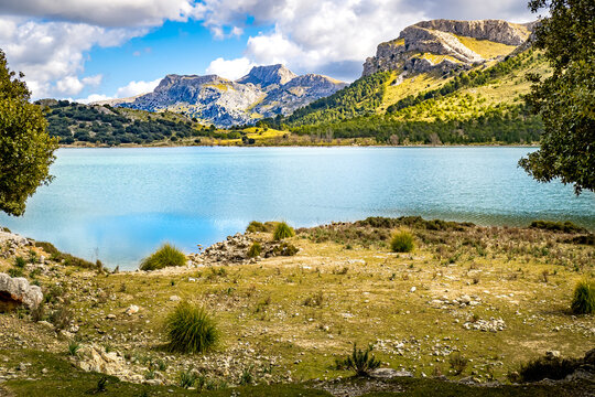 View from the lake shore of the artificial mountain lake embassament de c&uacute;ber to the mountain peaks of Morro de C&uacute;ber and Serra dels Teixos in the mountain ridge of serra de tramuntana nearby Escorca.