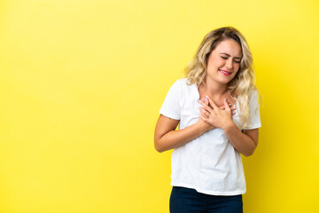 Young Brazilian woman isolated on yellow background having a pain in the heart