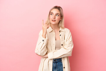 Young caucasian woman isolated on pink background pointing up a great idea