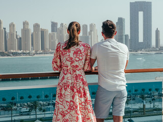 Stylish man and woman, standing on the empty deck of a cruise liner against the backdrop of the...