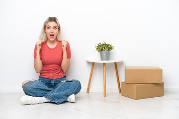 Young woman moving in new home among boxes isolated on white background celebrating a victory in winner position