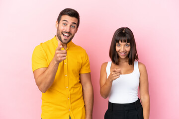 Young couple isolated on pink background points finger at you with a confident expression