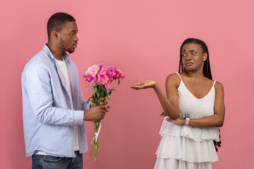 Black man making surprise for bored woman giving flowers