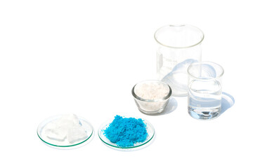 Alum Crystal and Copper(II) sulfate in Chemical Watch Glass on white laboratory table. Flake salt...