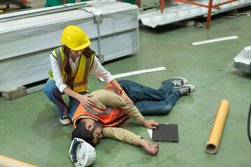 Asian male engineer accident lying unconscious on floor while working in factory.Safety female support helping him first aid accident