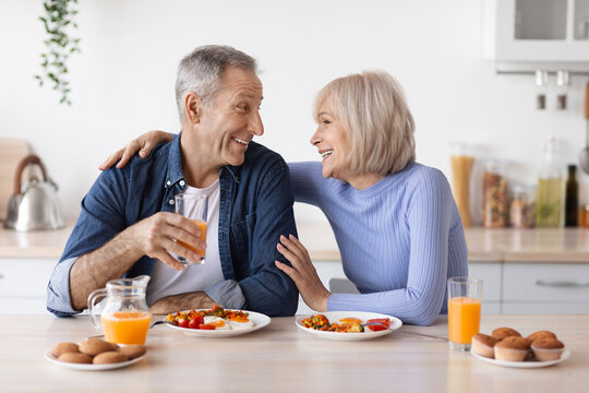 Happy elderly man and woman having lunch at home