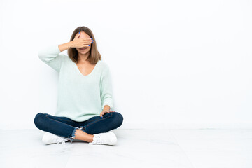 Young caucasian woman sitting on the floor isolated on white background covering eyes by hands. Do not want to see something