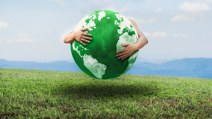 hand hugging a green globe on the grass. environmental concept on earth day