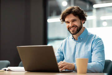 Portrait of smiling Arab man using laptop and posing