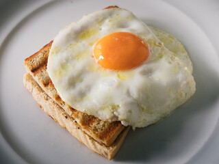 Croque Monsieur Ham and Cheese Toast with a Fried Egg Sunny Side Upon a White Plate
