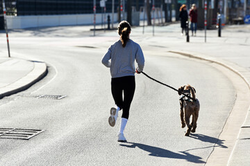 Läuferin mit einem Hund auf der Ringstraße in Wien, Österreich, Europa