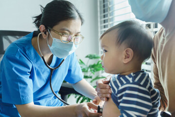 Asian pediatrician or doctor or nurse examining and listening lungs of little baby boy with...