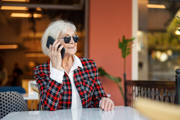 Fototapeta premium Portrait of pensioner lady using smartphone in city