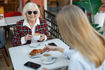 Happy retired woman having coffee at street cafe
