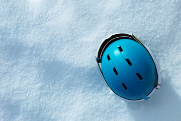 Blue ski helmet in the snow and mask, view from above,