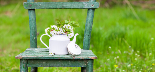 Dekoration mit einem alten Stuhl und einer Kaffekanne in einem Natur Garten