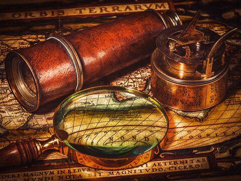 Travel geography navigation concept background - vintage retro effect filtered hipster style image of old vintage retro compass with sundial, spyglass and magnifying glass on ancient world map