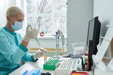 Mature female laborant doing biochemical tests for patients