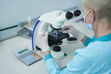 Mature woman doing blood test with microscope