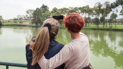 Fototapeta premium mom and daughter walking in the park and momandoce selfie