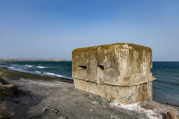 Fototapeta premium The bunker stands on the beach near the Black Sea with a war on the background of a cloudy sky