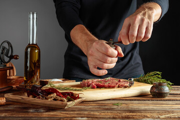 Chef prepare steak. Uncooked steak in sauce with spices an rosemary.
