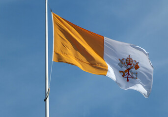 vatican state flag flying against a bright blue sunlit sky