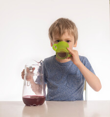 the boy drinks juice from a cup poured from a decanter