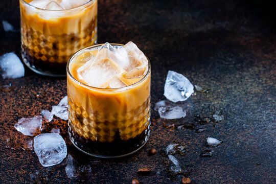 Trendy alcoholic cocktail drink with vodka, coffee liqueur, cream and ice on dark background,  copper bar tools. Negative space