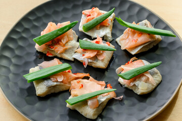 Salted herring pieces with pickled ginger, pepperoni and chives. Appetizer food