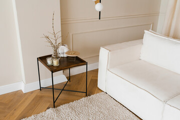 Stylish Scandinavian interior of a cozy living room with a white sofa and coffee table and tree branches in a vase © Sunshine