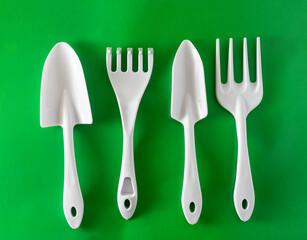 white garden tools shovels and rakes on a green background