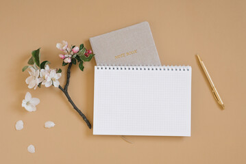 Office desk. Notepad or planner, pen and delicate apple blossoms. View from above. Flat lay. Home office workspace. Copy space, mock up