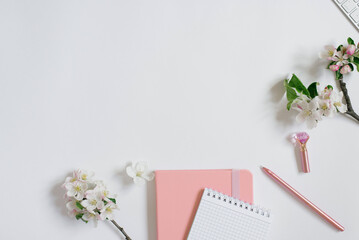 Blogger workplace: notebooks with pen and apple flowers on a white background with copy space. Flat lay