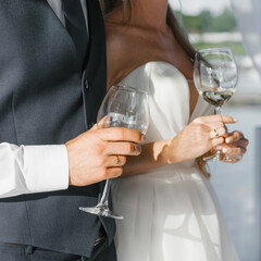 Champagne glasses in the hands of the bride and groom close-up