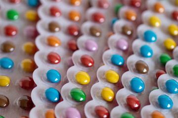 A lot of colorful round candies in a blister, packs are laid out at different angles