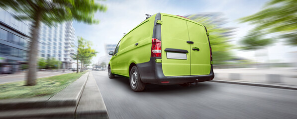 Green commercial van driving in the city - obrazy, fototapety, plakaty