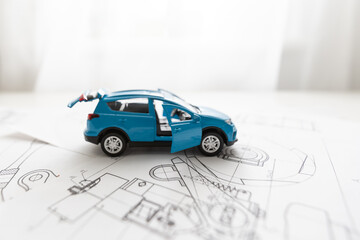 Small toy car and wooden toy house close up image on blueprint background.
