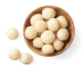 Shelled Macadamia nuts in the wooden bowl, isolated on white background, top view.